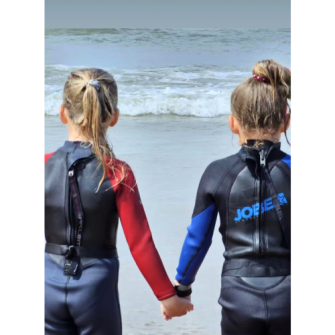 Twee meisjes hand in hand in de branding van de zee